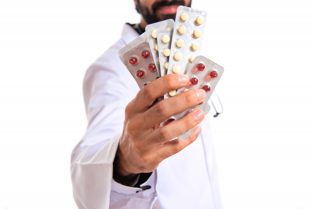 Doctor holding blister packs of painkillers, illustrating the link between painkillers and kidney damage