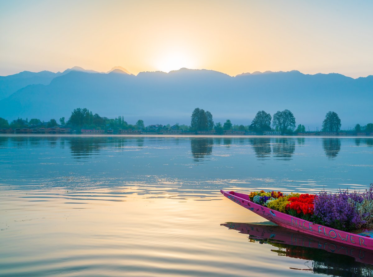 Sunrise over Dal Lake in Kashmir with a shikara boat in the foreground