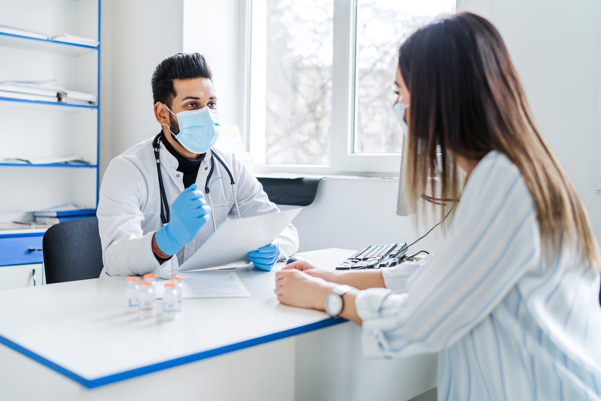Doctor in a white coat talking with a patient during a clinic consultation