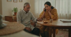 Woman calling for help on her phone while sitting beside her elderly father at home, stroke warning signs